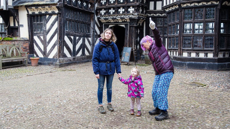 Family exploring the courtyard of the house at Little Moreton Hall, Cheshire